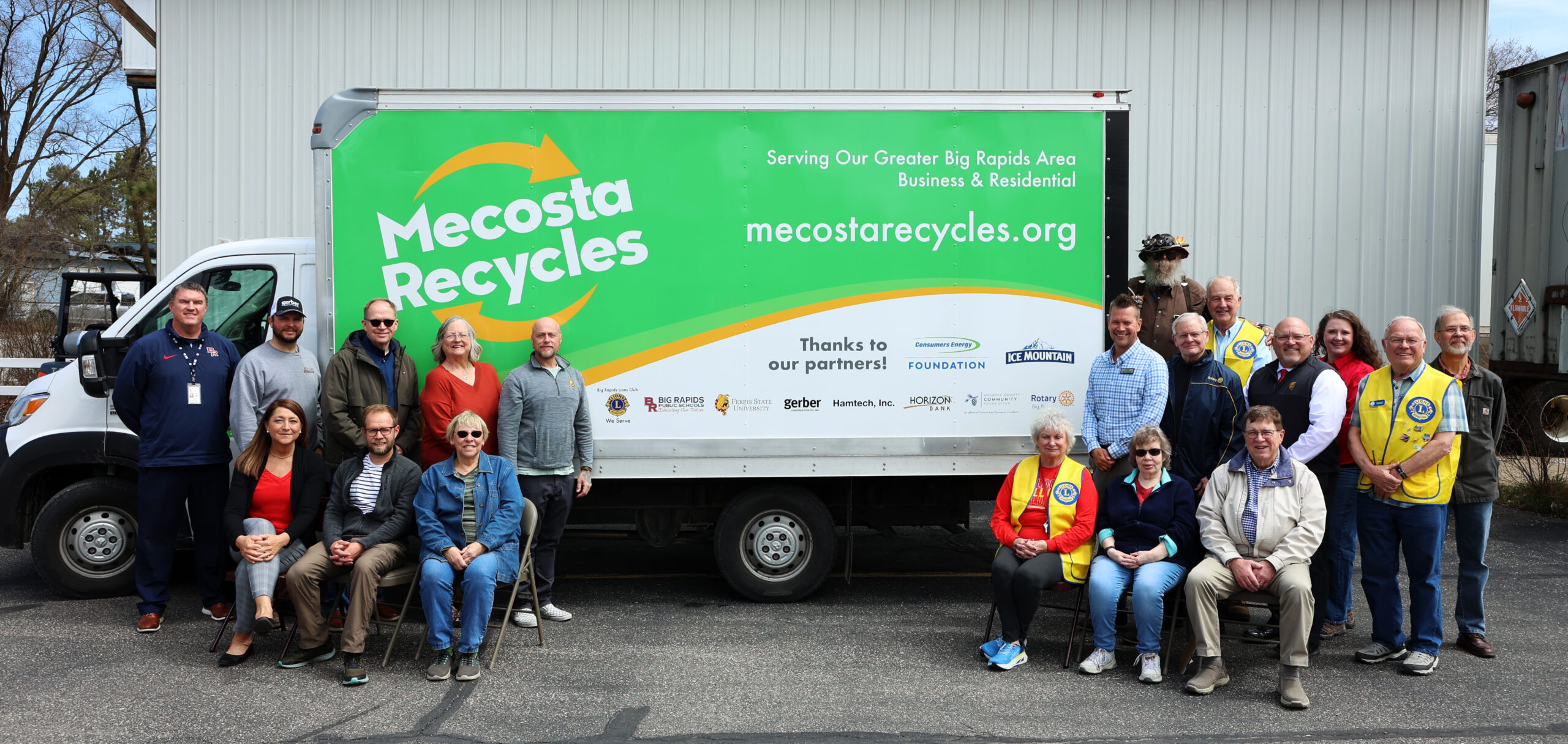 A group of board members and business representatives pose in front of the new box truck used for business pick ups.